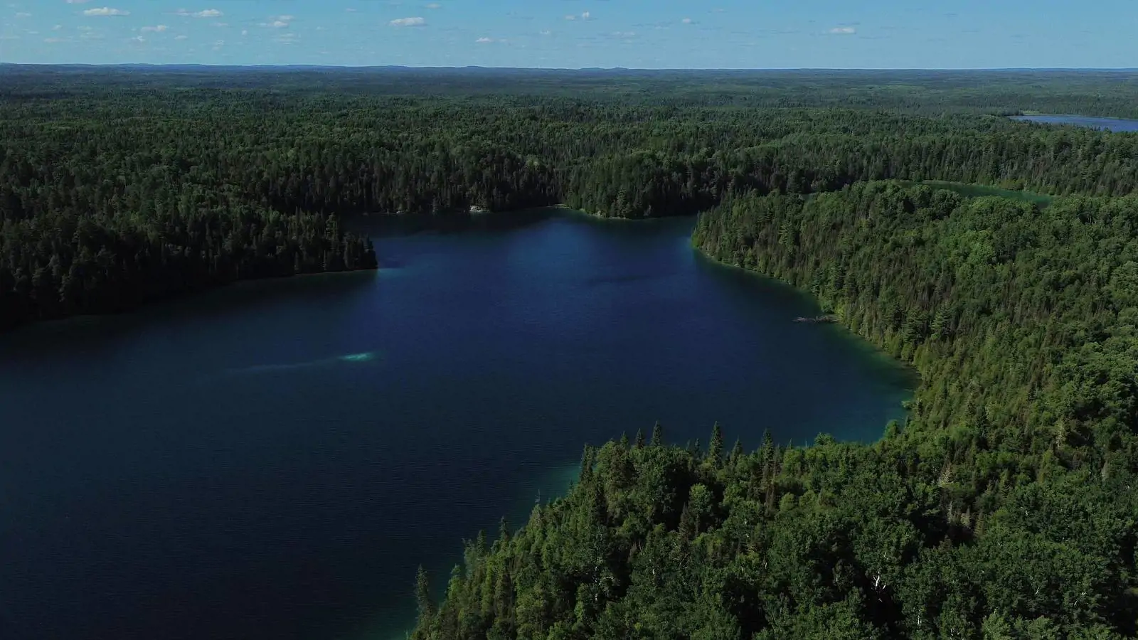 Aerial view of a deep blue northern Ontario lake stretching to the horizon